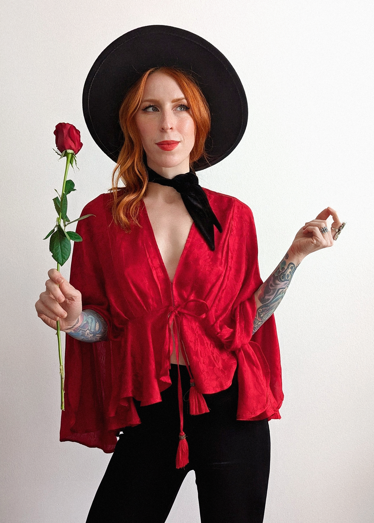 70s inspired ruby red satin batwing cape top with deep v-neckline and tonal floral pattern throughout the red satin fabric. Tassel tie details at front and red lace at back