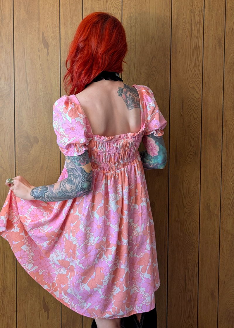 back view of a person wearing a pink and orange floral babydoll shirred dress
