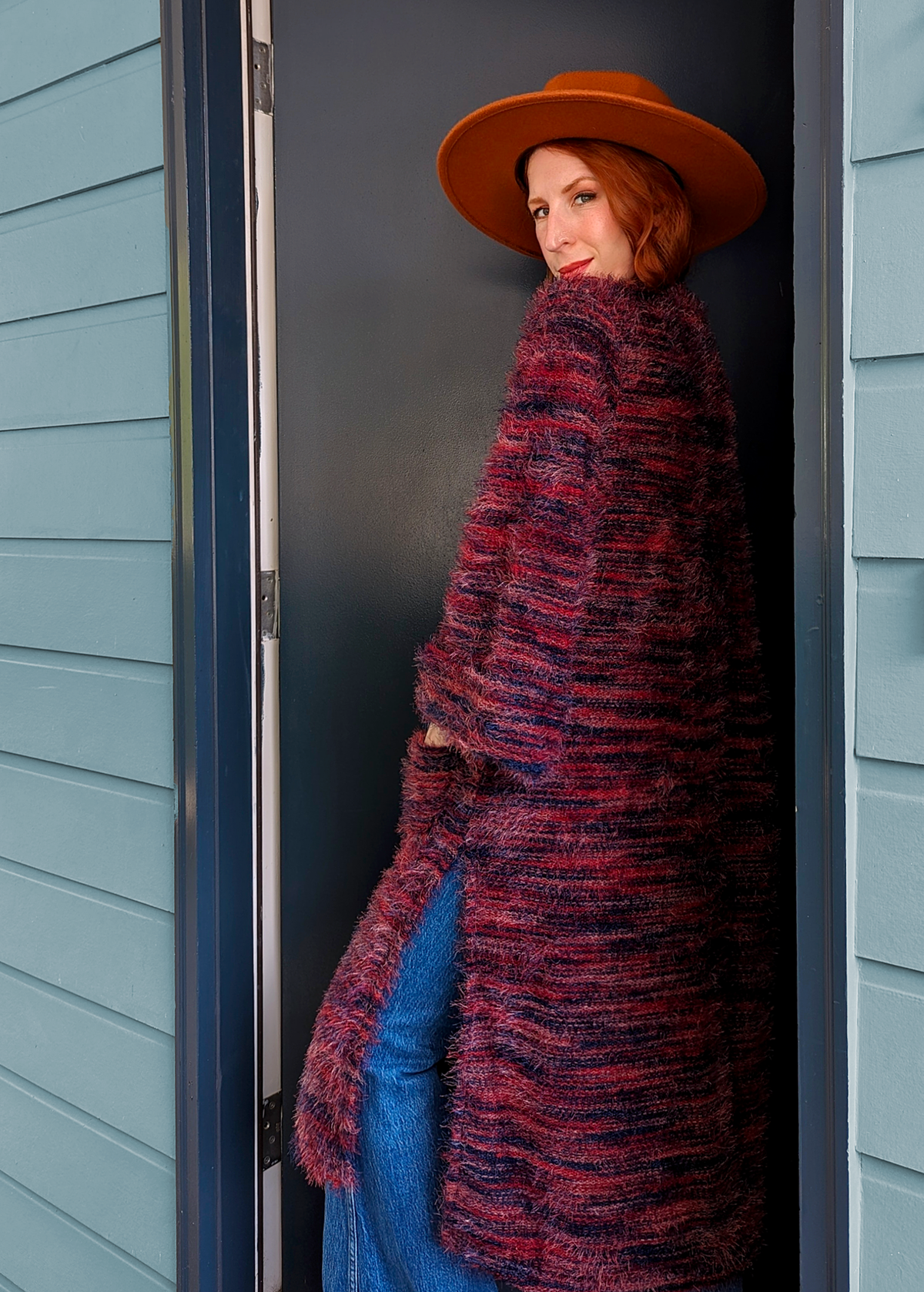 70s inspired fuzzy eyelash knit cardigan duster with a midi-maxi length. Features an open front, wide bell cuffed sleeves, and a pink, red, and purple spacedye design. Slits at sides for easy movement.