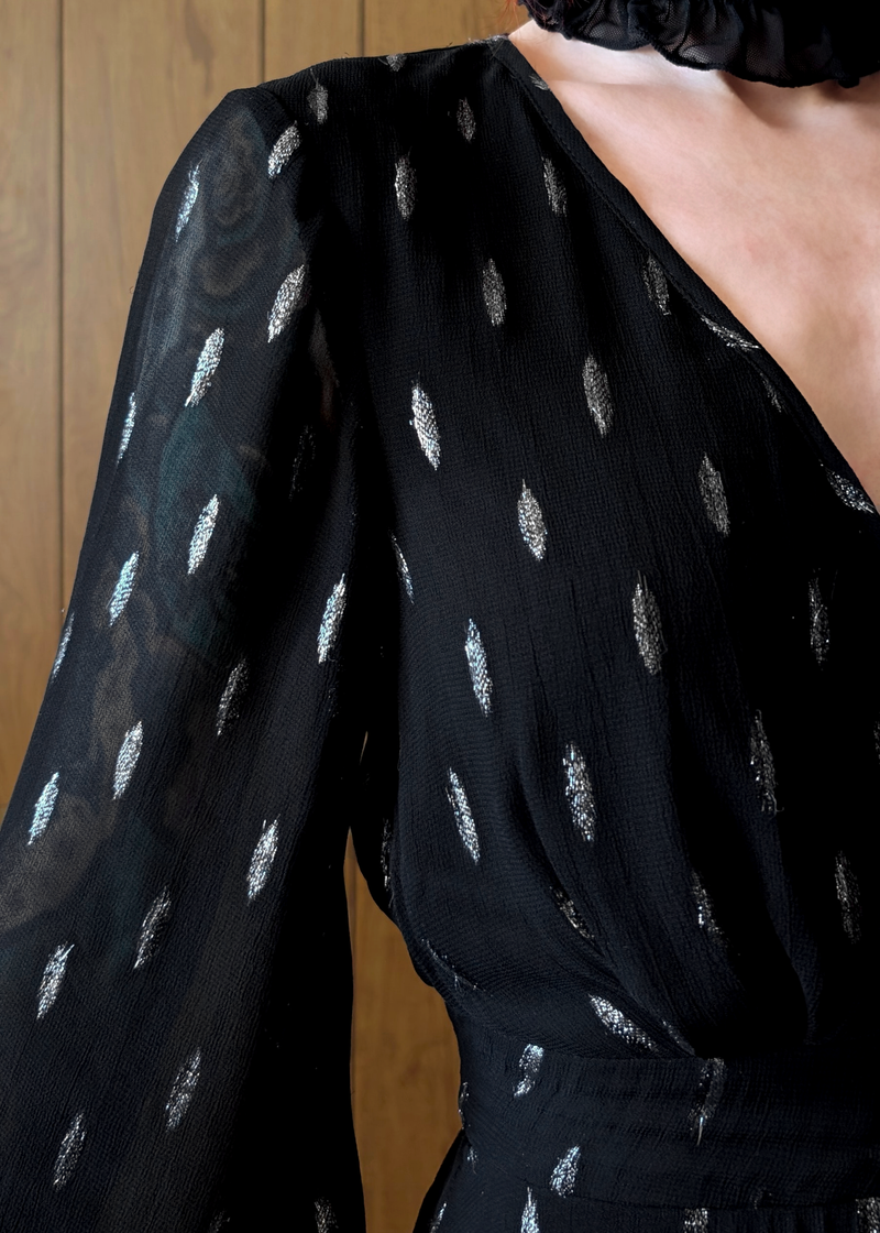 Details of a black dress with silver patterns on a wooden background