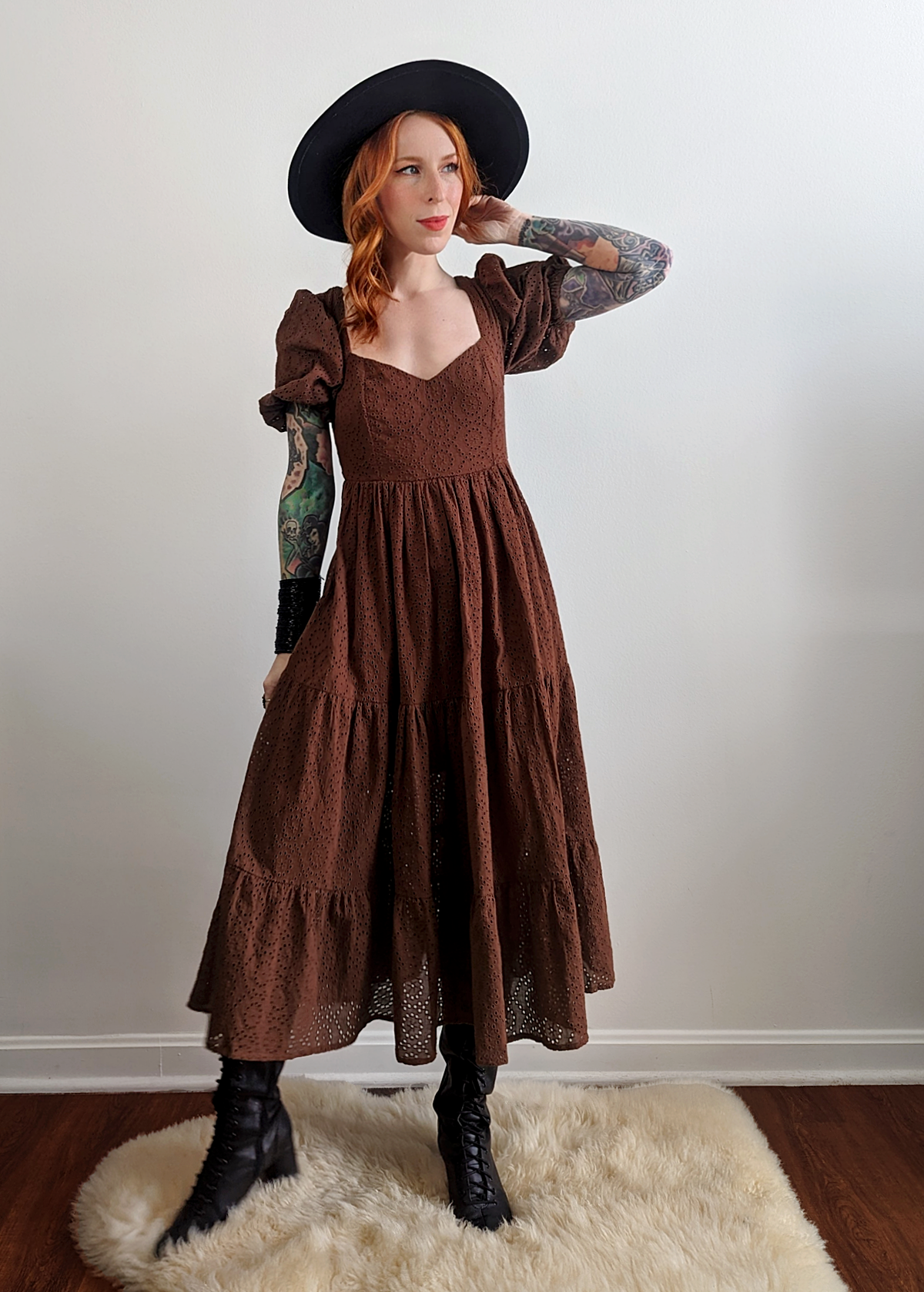 70s inspired prairie dress made of 100% eyelet cotton in a walnut brown colorway. Features puff sleeves, sweetheart neckline, smocked back with tie closure, and ruffled tiered skirt. 