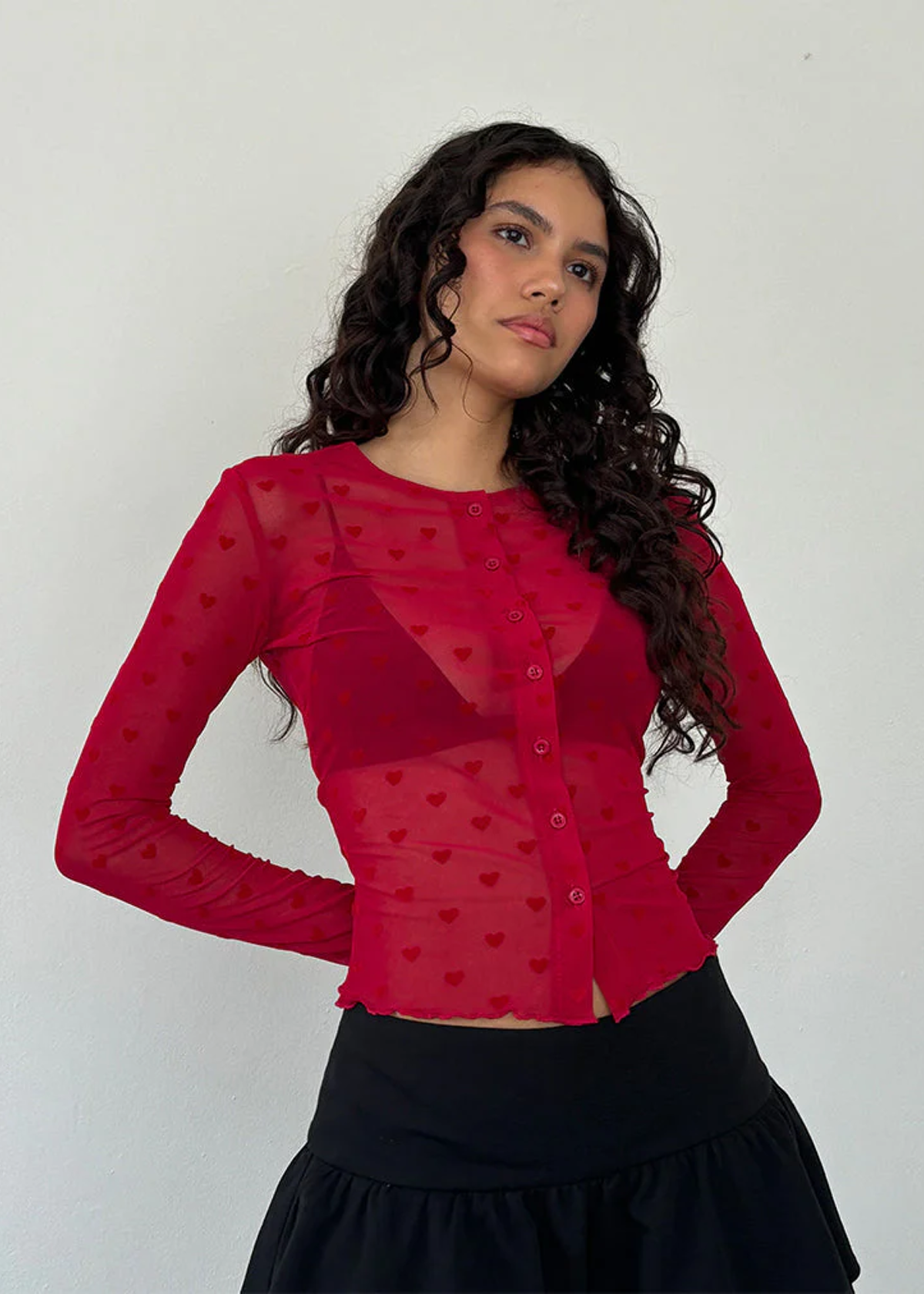 90s inspired Valentine deep red slinky mesh button front top with red flocked velvet hearts all over. Lettuce trim at cuffs and hem. By Motel Rocks