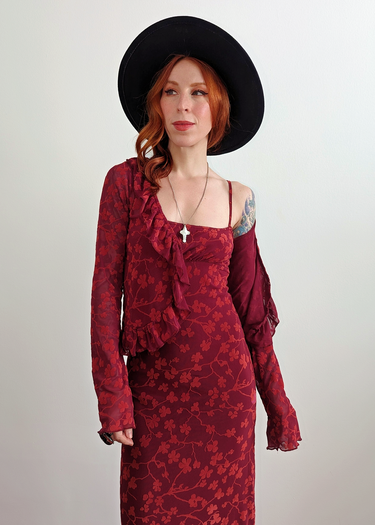 90s inspired burgundy red ruffled cardigan top made of a slinky mesh fabrication with flocked velvet floral design. Deep v-neckline, hook and eye closure at front. Long sleeves. By Motel Rocks