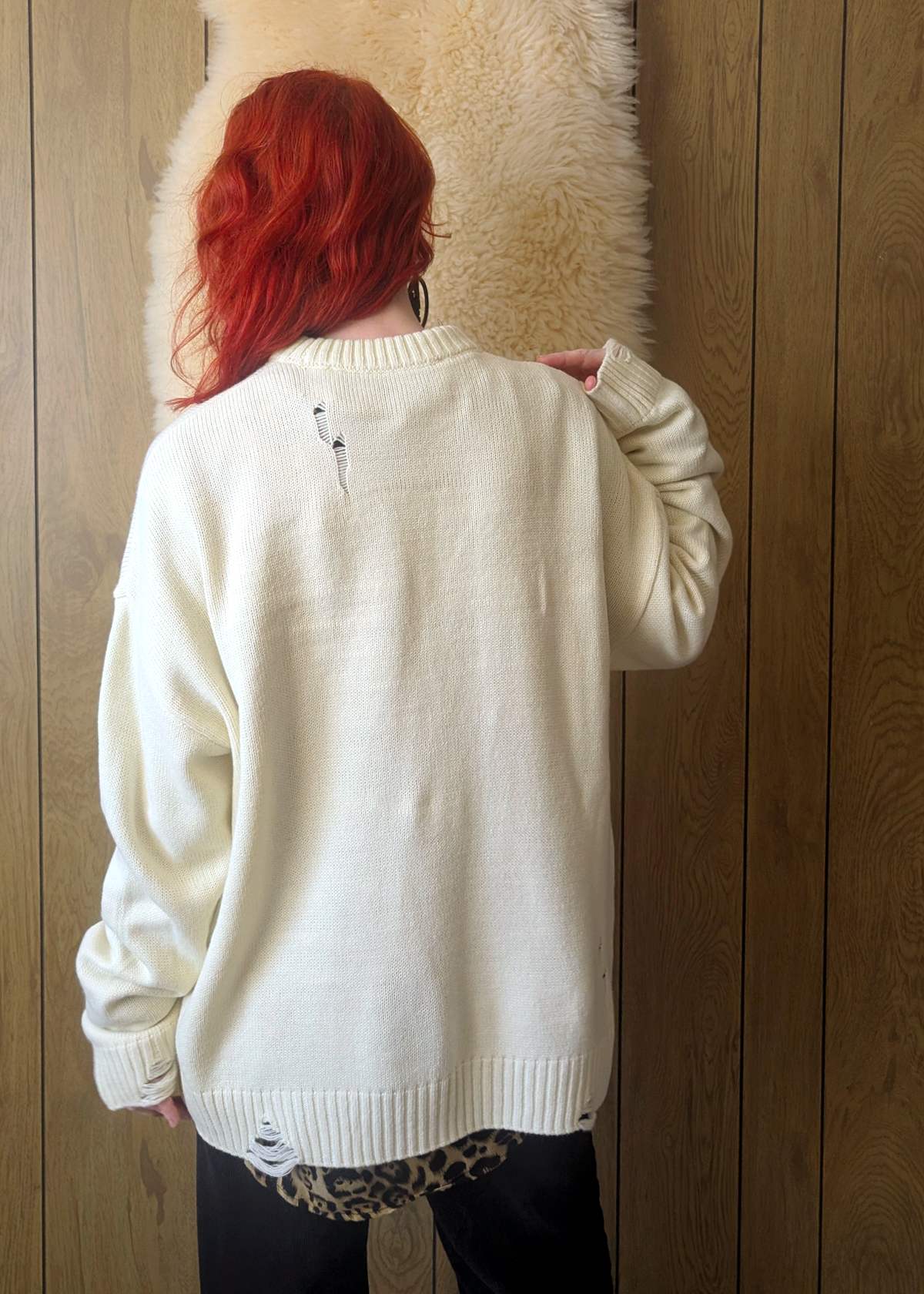 Person wearing a cream sweater with a wooden panel background