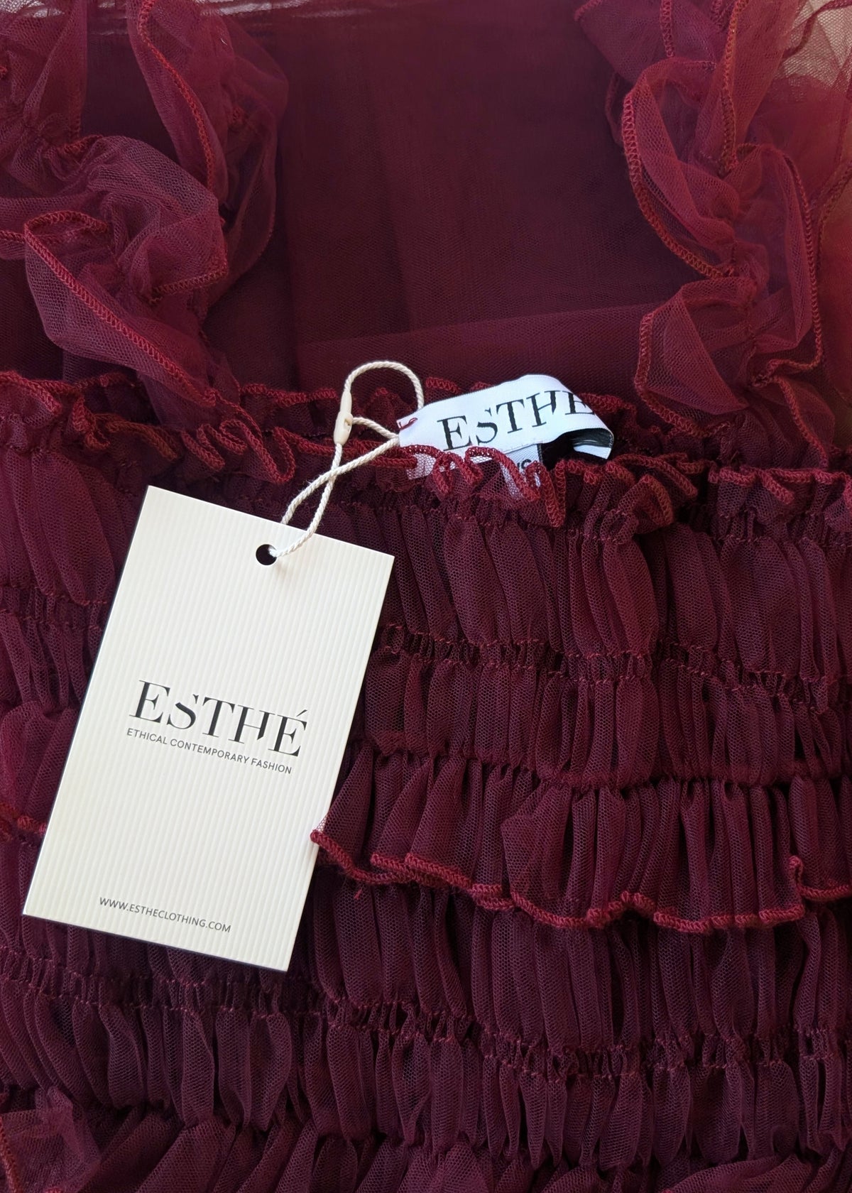Red ruffled fabric with 'Esthe' tag in the foreground