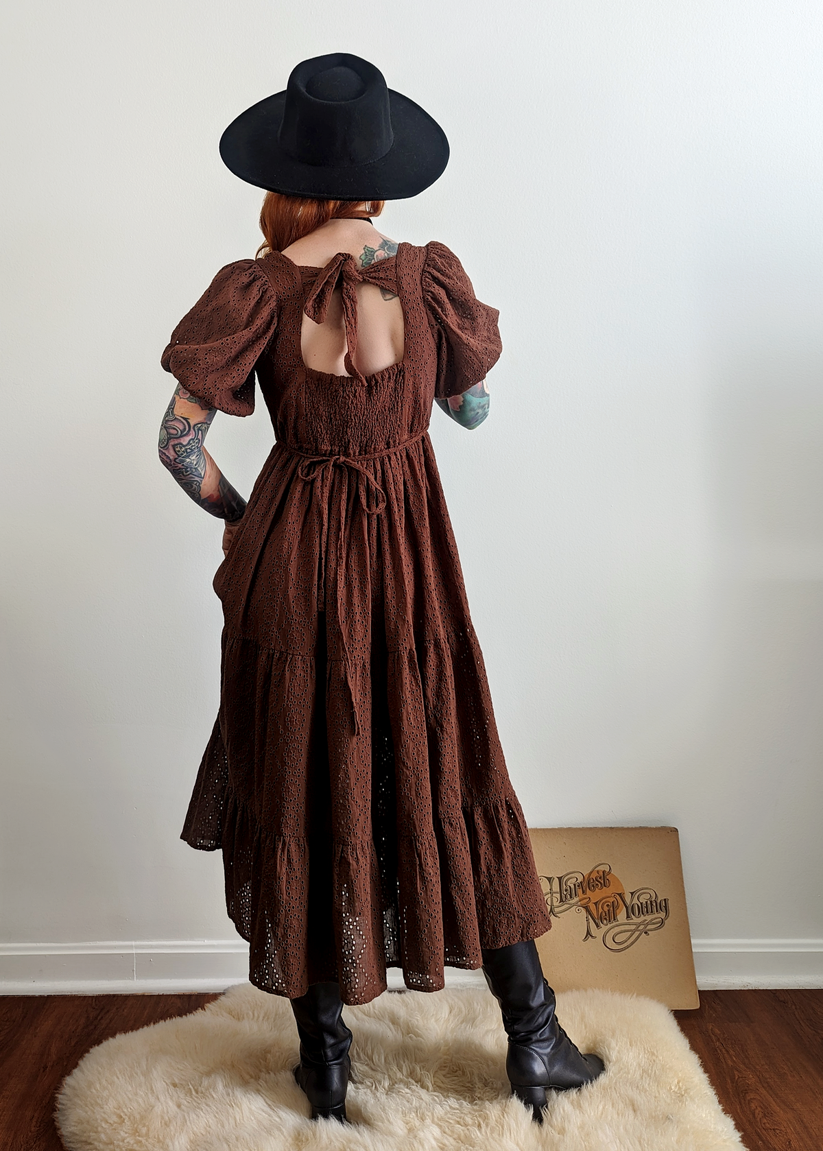 70s inspired prairie dress made of 100% eyelet cotton in a walnut brown colorway. Features puff sleeves, sweetheart neckline, smocked back with tie closure, and ruffled tiered skirt. 