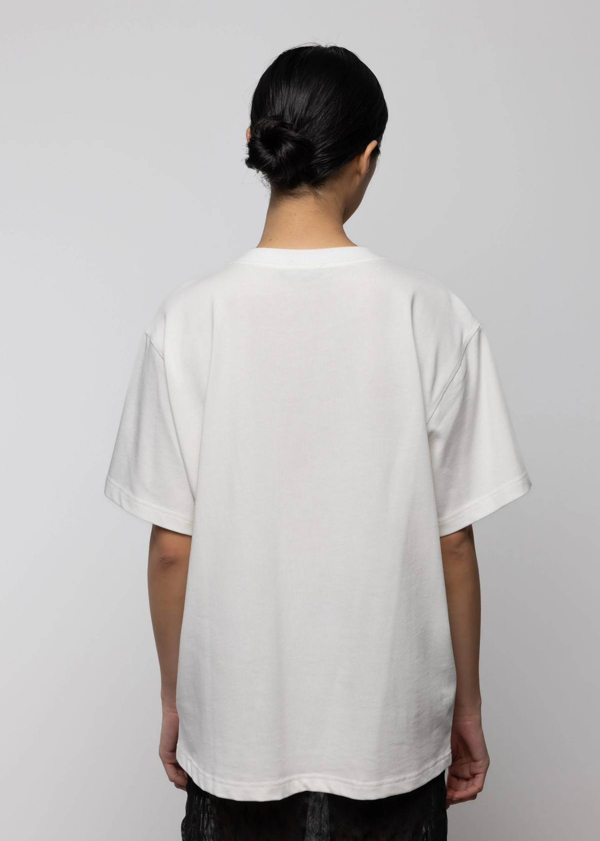 Person wearing a plain white t-shirt against a light gray background