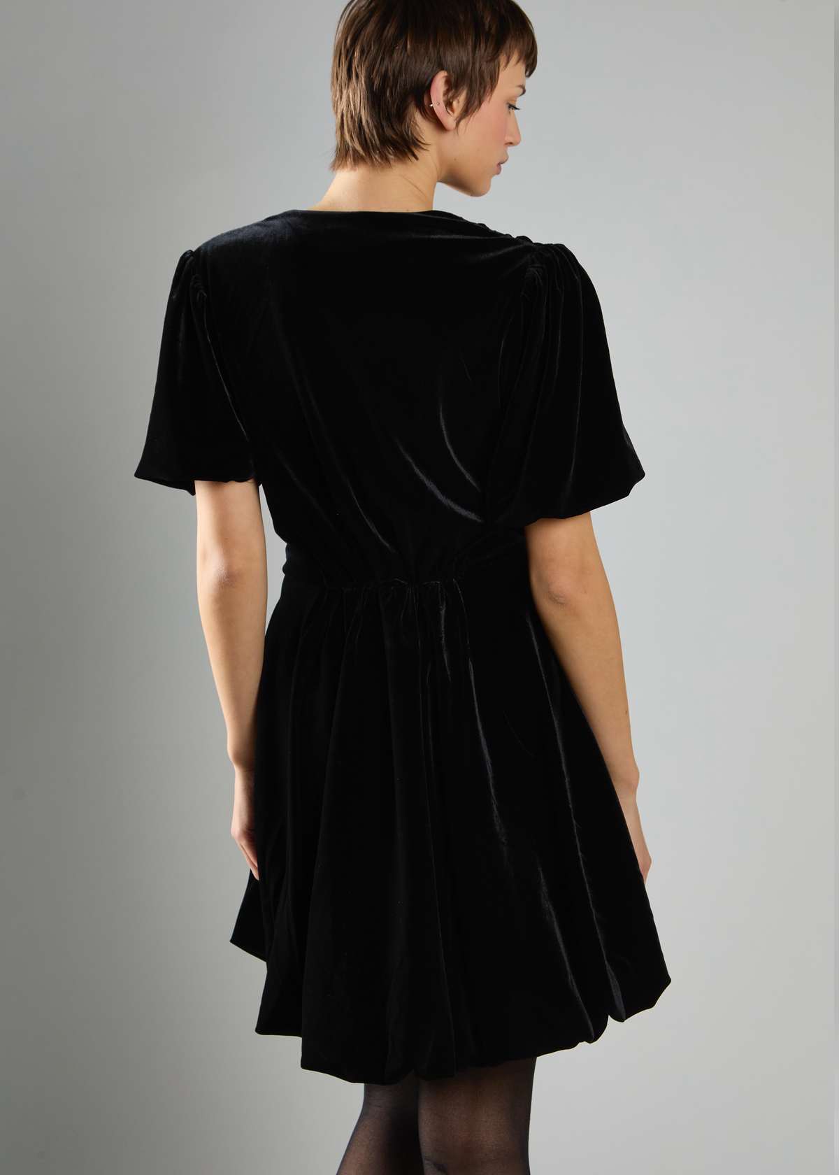 Woman wearing a black dress against a gray background