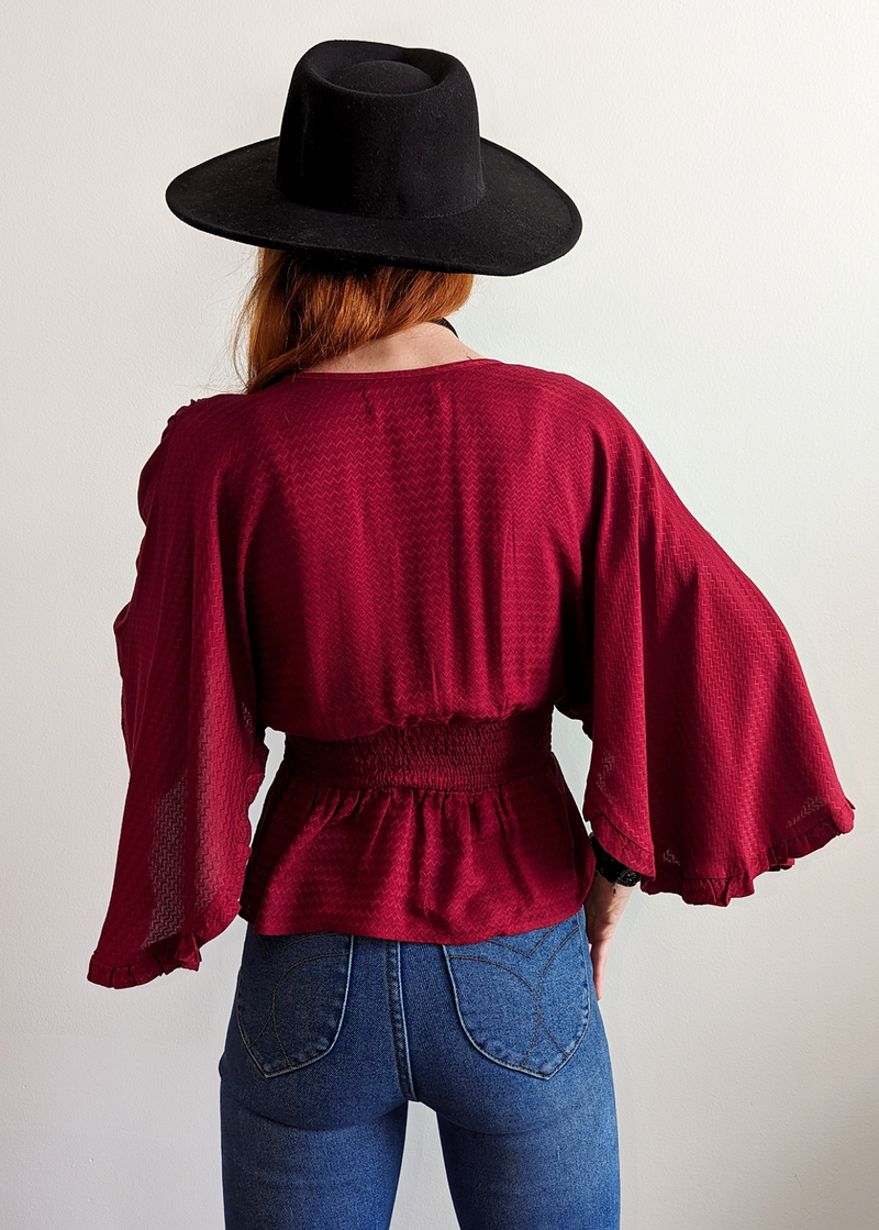 Stevie Nicks Vibes. Deep red top with batwing cape sleeves, smocked bodice, and tassel tie details at front