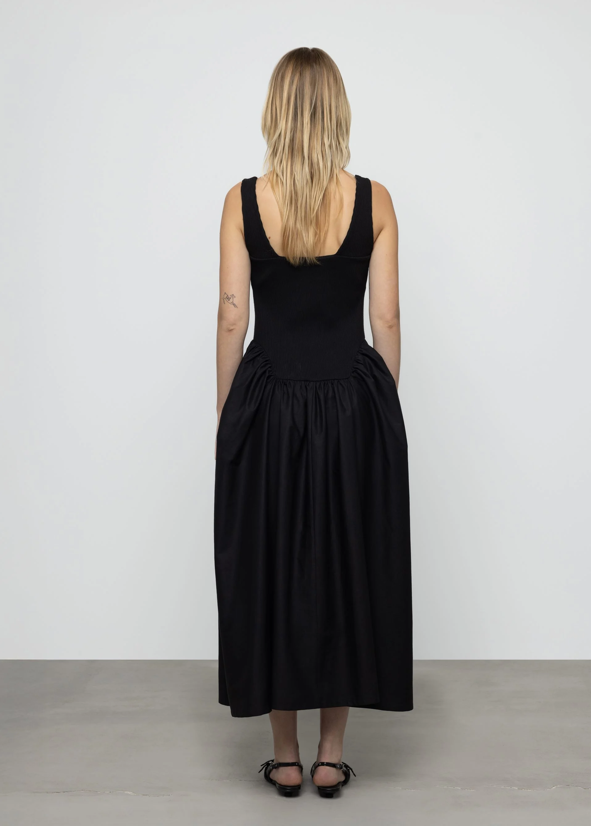 Woman wearing a black dress standing against a white background