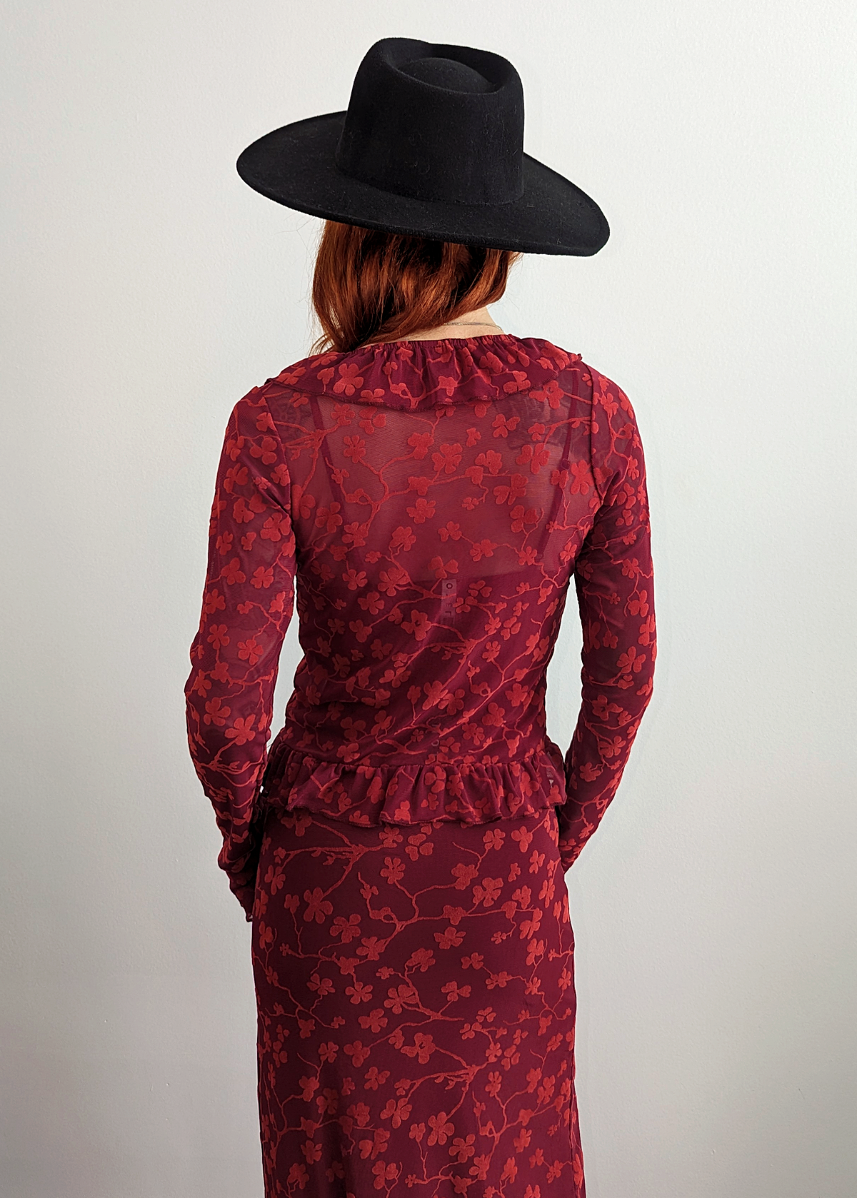 90s inspired burgundy red ruffled cardigan top made of a slinky mesh fabrication with flocked velvet floral design. Deep v-neckline, hook and eye closure at front. Long sleeves. By Motel Rocks