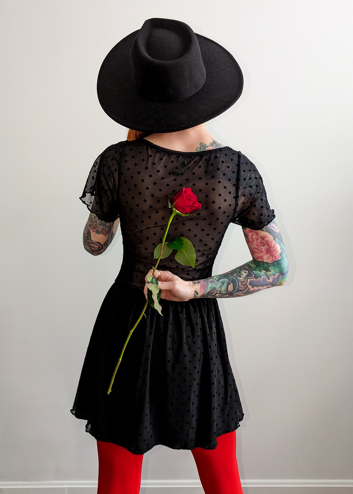 90s inspired black mesh mini dress with black velvet flocked dots allover. Features flutter short sleeves, v-neckline with red satin rosette, sheer waist, and floaty skirt. By Motel Rocks