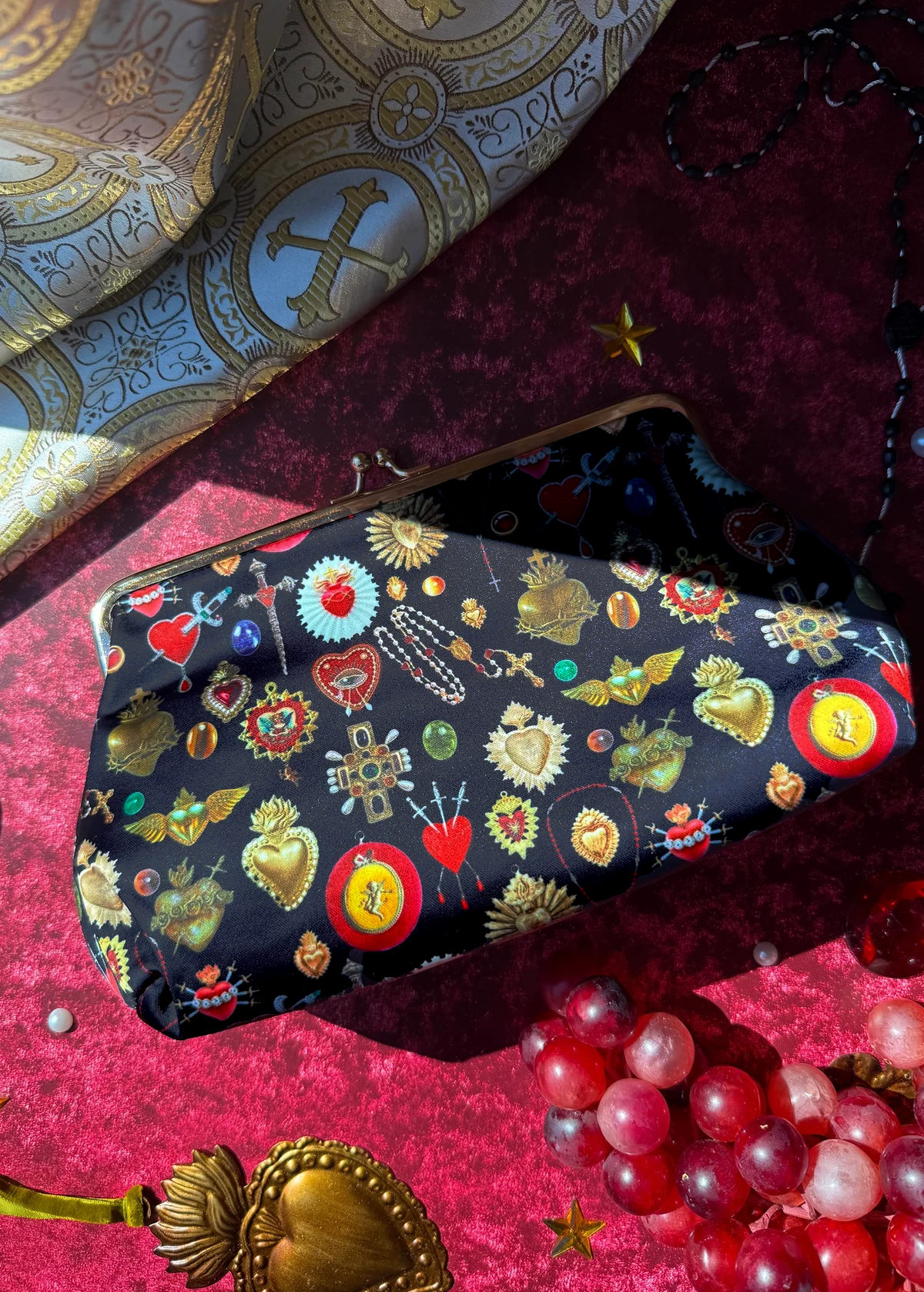 Decorative kiss lock clutch bag with colorful sacred heart  on a textured red fabric background