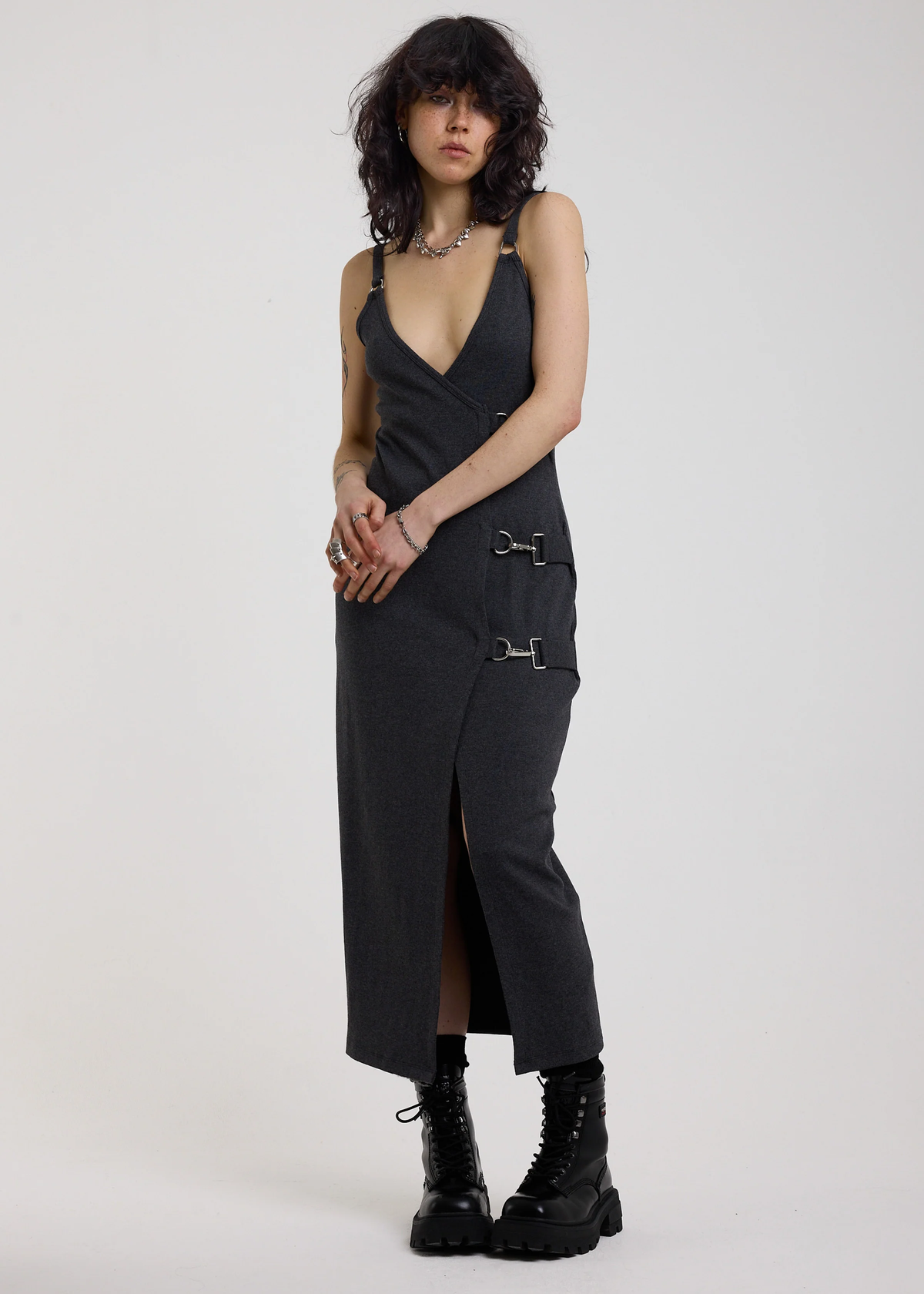 Woman wearing a charcoal grey ribbed tank midi dress with buckles against a white background