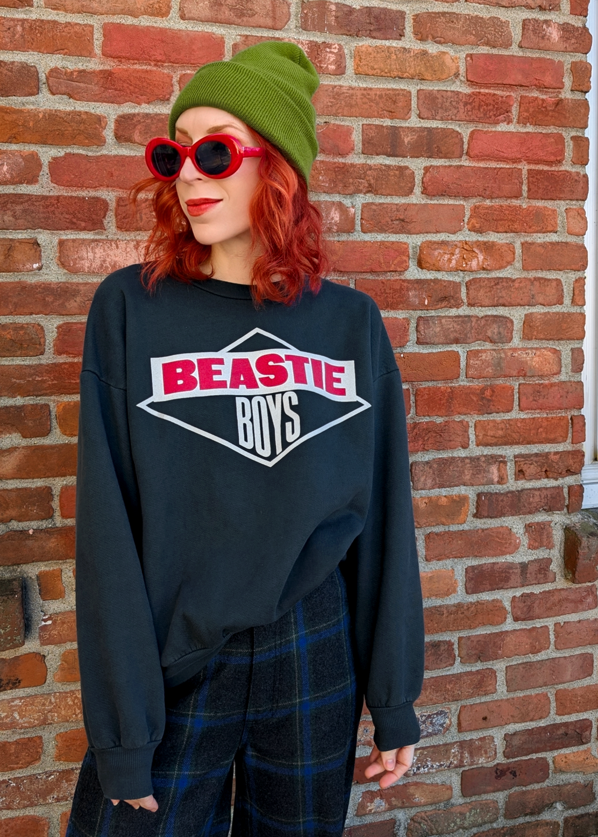 Person wearing a Beastie Boys sweatshirt in front of a brick wall