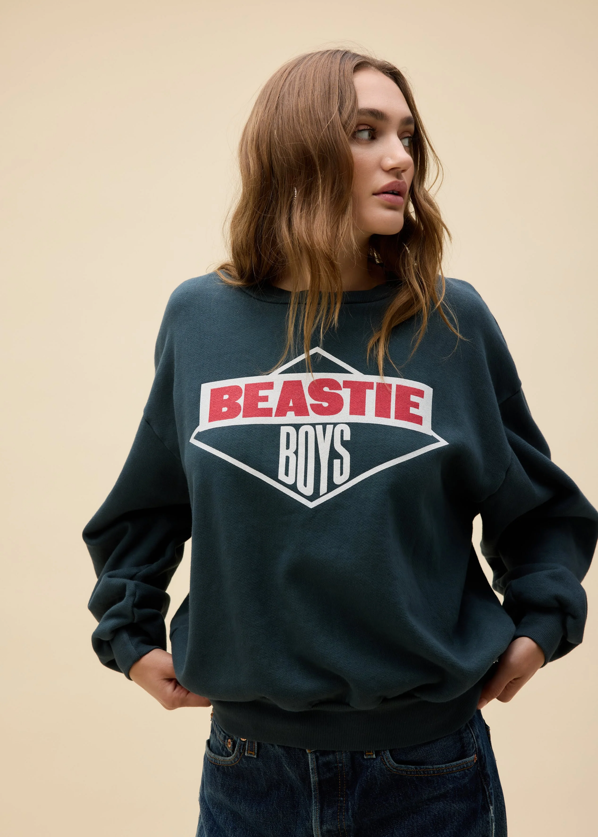 Person wearing a black 'Beastie Boys' sweatshirt against a beige background