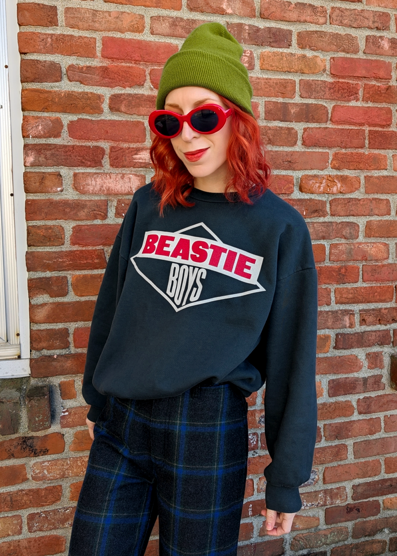 Person wearing a 'Beastie Boys' sweatshirt in front of a brick wall