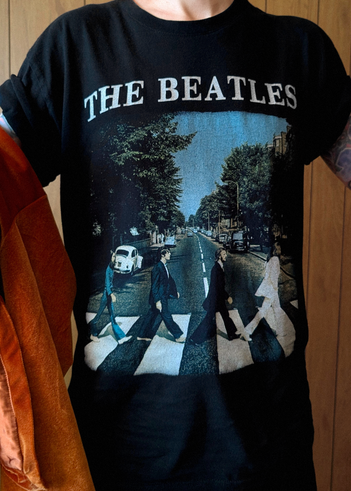 Black t-shirt with The Beatles Abbey Road design worn by a person.