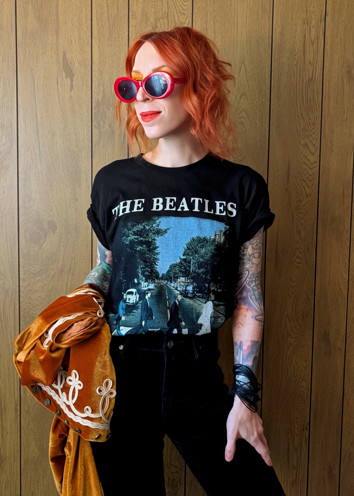 Person wearing a black 'The Beatles' t-shirt against a wooden panel background
