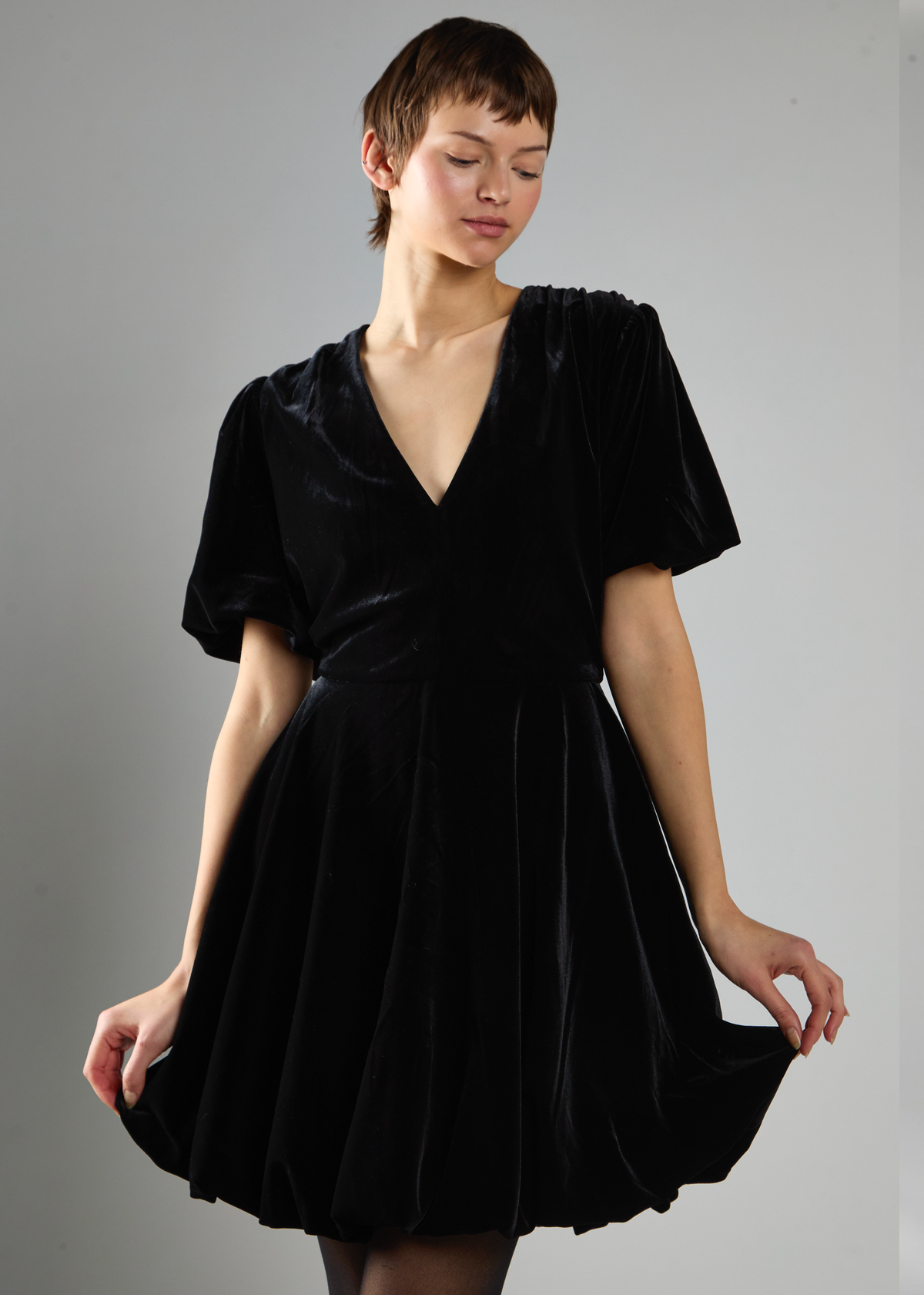 Woman wearing a black velvet dress against a gray background
