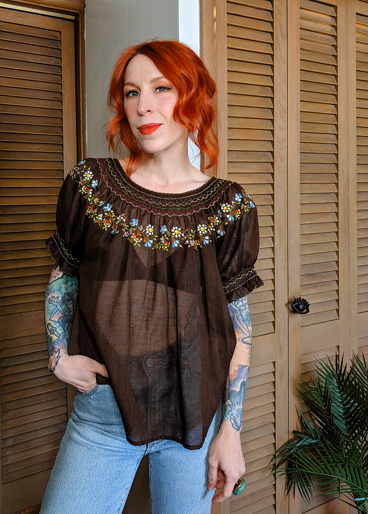 Vintage 1970s gauzy cotton prairie Penny Lane blouse featuring a round neckline, short puff sleeves, and colorful floral embroidery along neckline. Chocolate brown colorway
