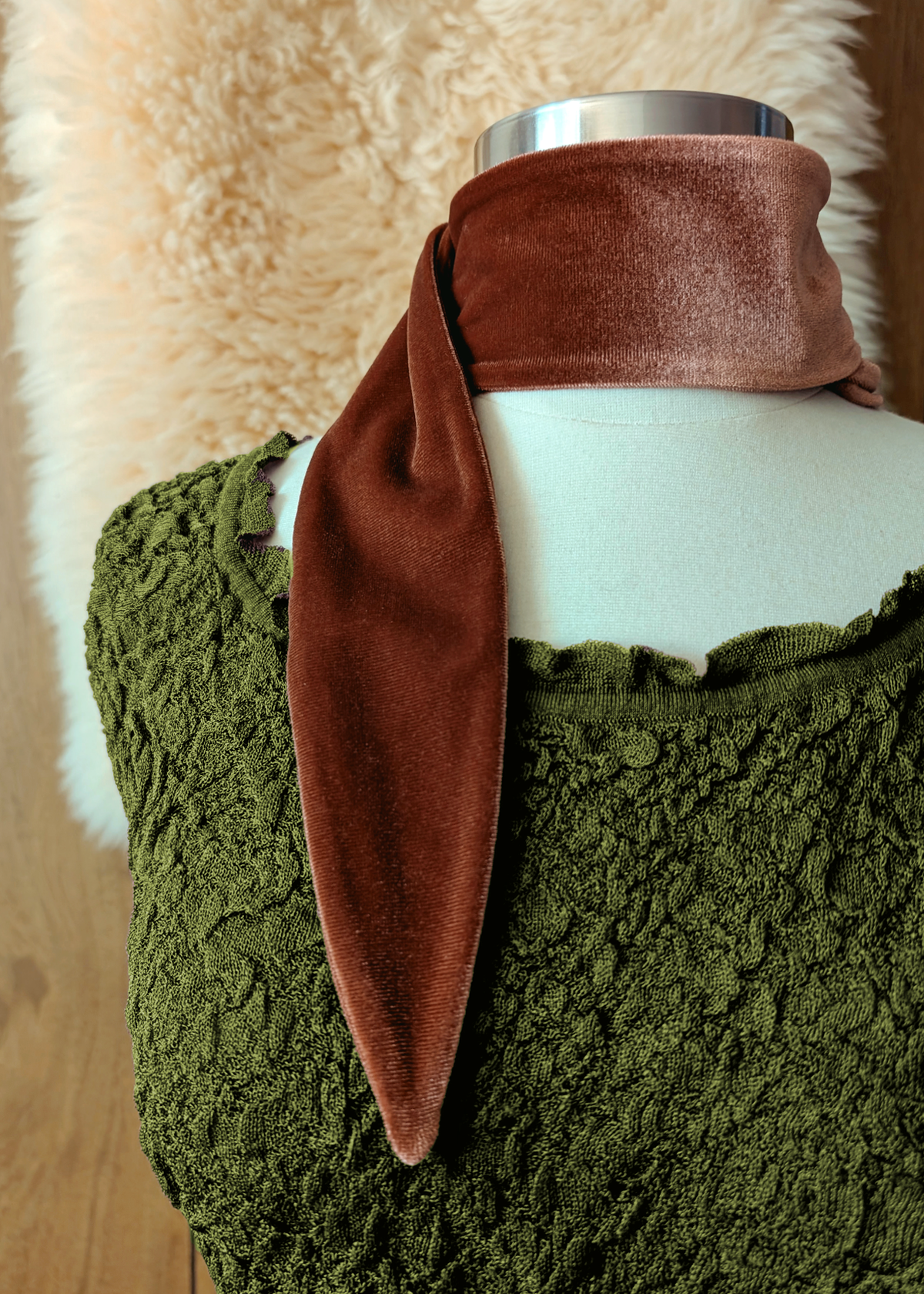 Brown velvet scarf tied around a white mannequin's neck with a green texture dress