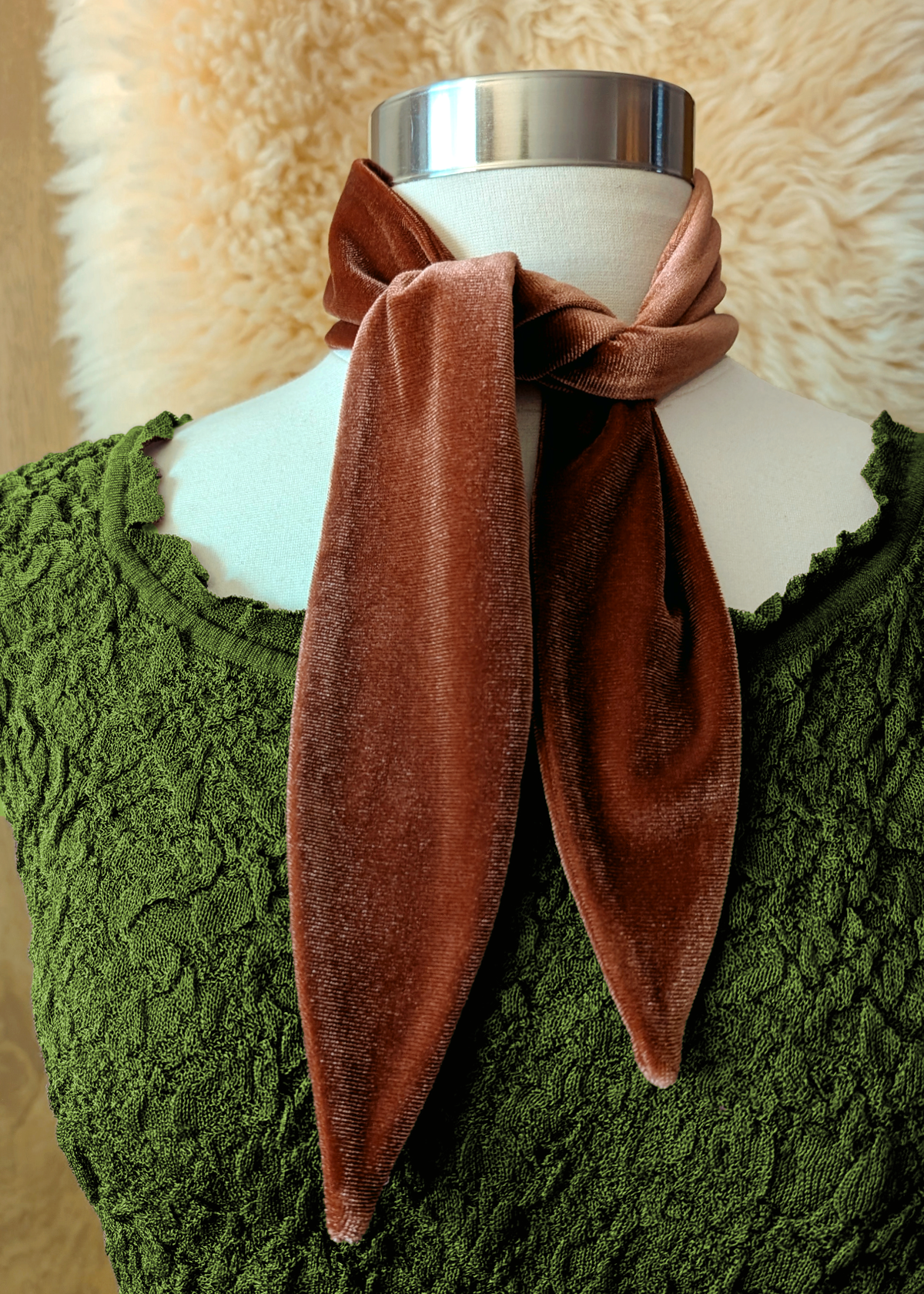 Brown velvet scarf tied around a white mannequin's neck with a green texture dress