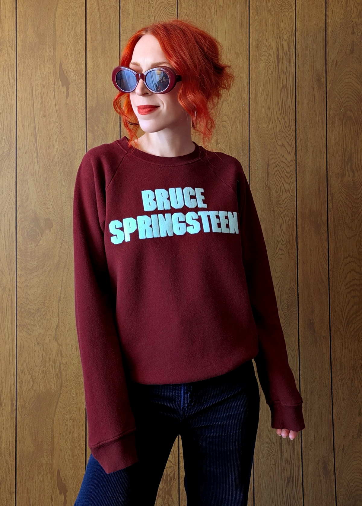 Person wearing a maroon sweatshirt with 'BRUCE SPRINGSTEEN' text against a wooden background