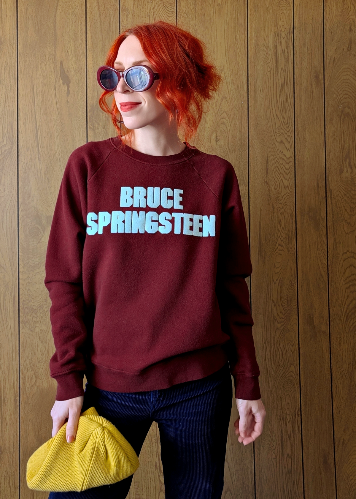 Person wearing a maroon sweatshirt with 'BRUCE SPRINGSTEEN' text against a wooden background