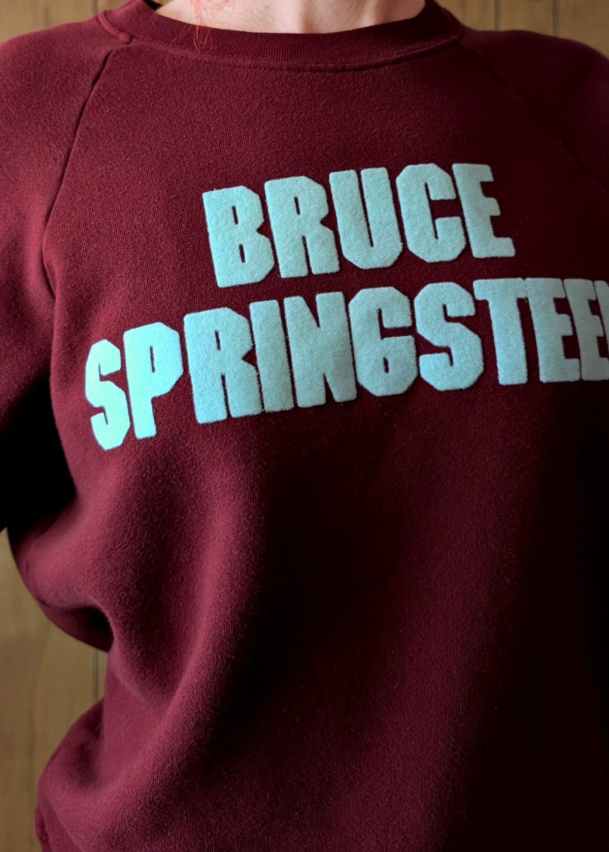 Maroon sweatshirt with 'BRUCE SPRINGSTEEN' printed in light mint / aqua  