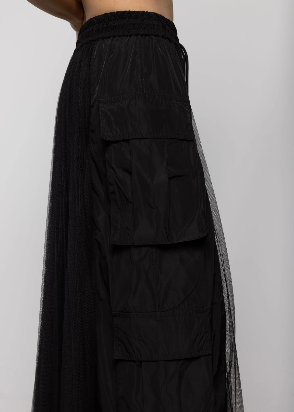 Black sheer skirt with solid black nylon cargo pockets at sides on a plain background