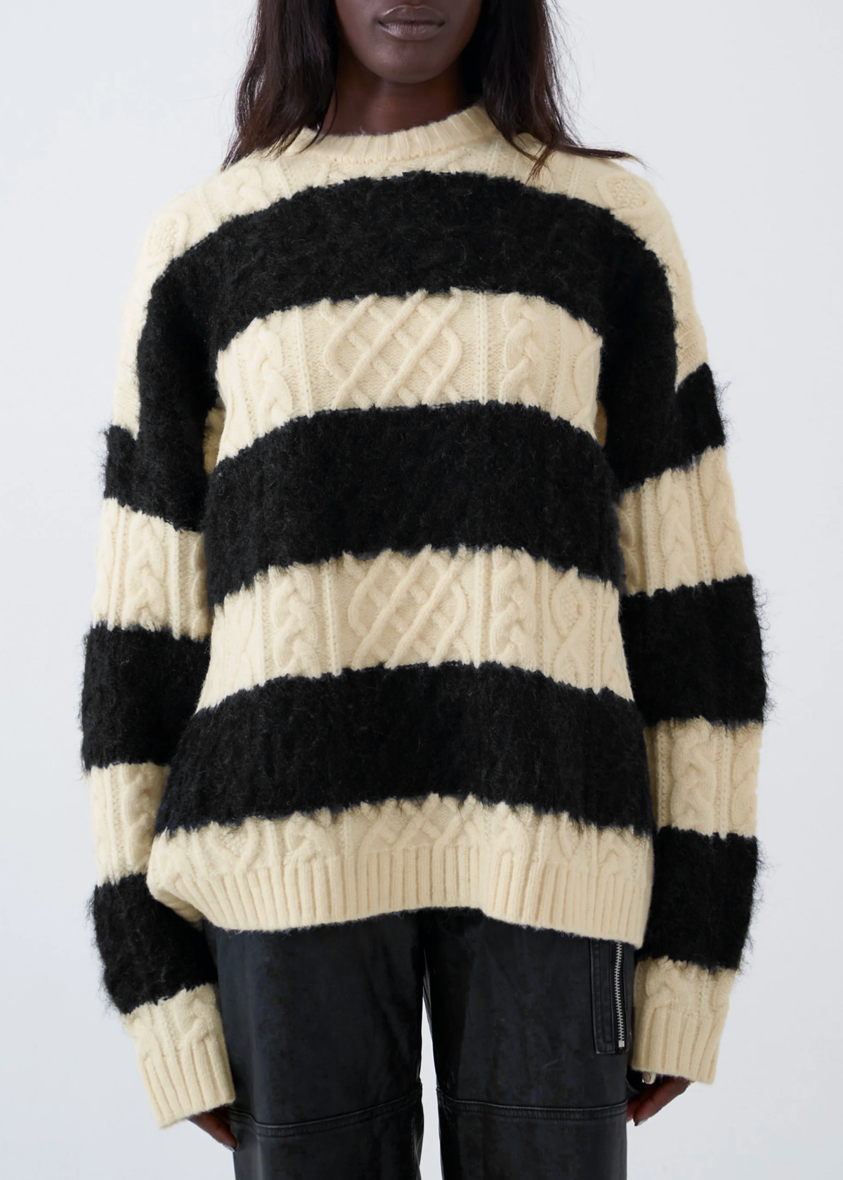 Person wearing a black and cream striped sweater against a white background