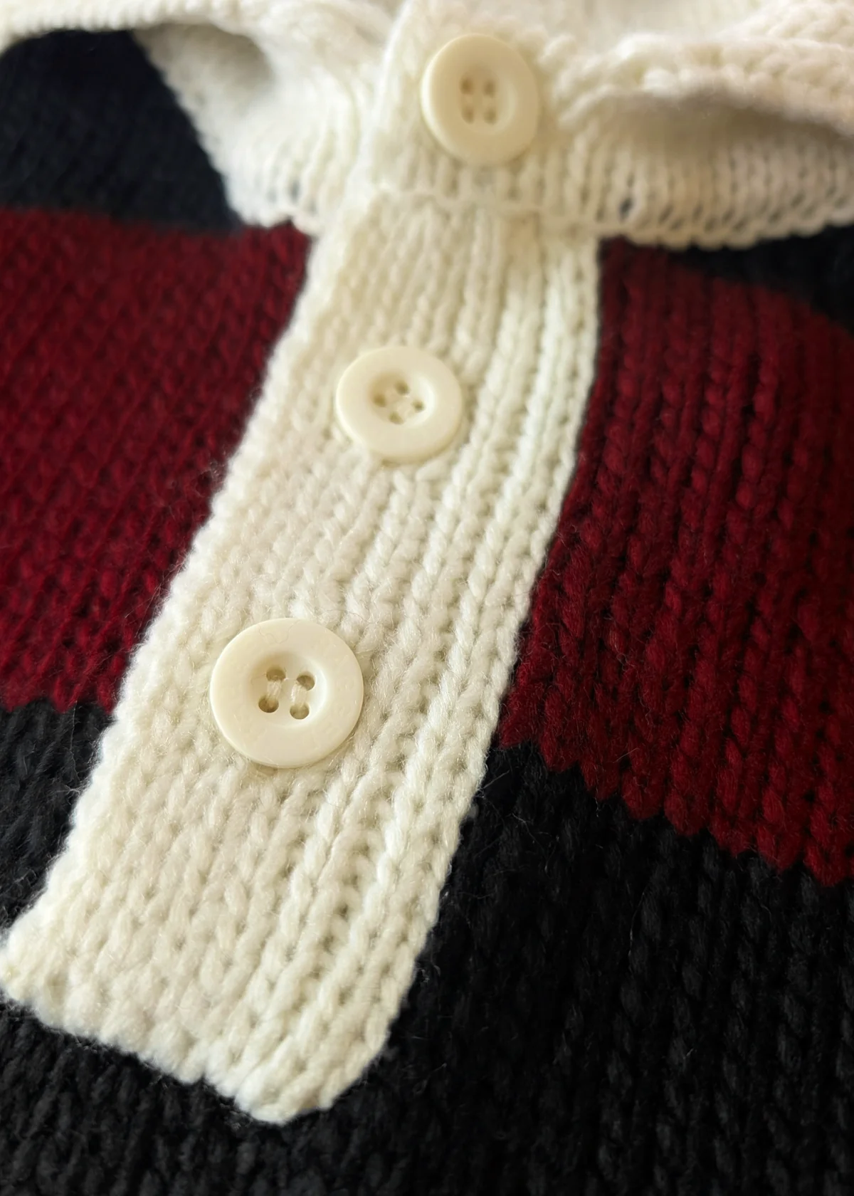 Close-up of a knitted polo sweater with buttons on a red and black stripe fabric