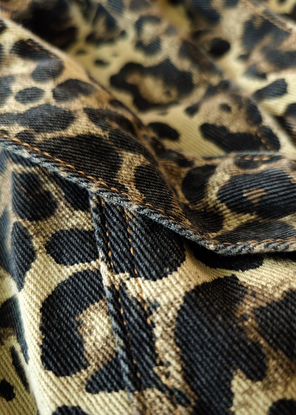 Close-up of leopard print  denim fabric with a focus on texture and pattern.
