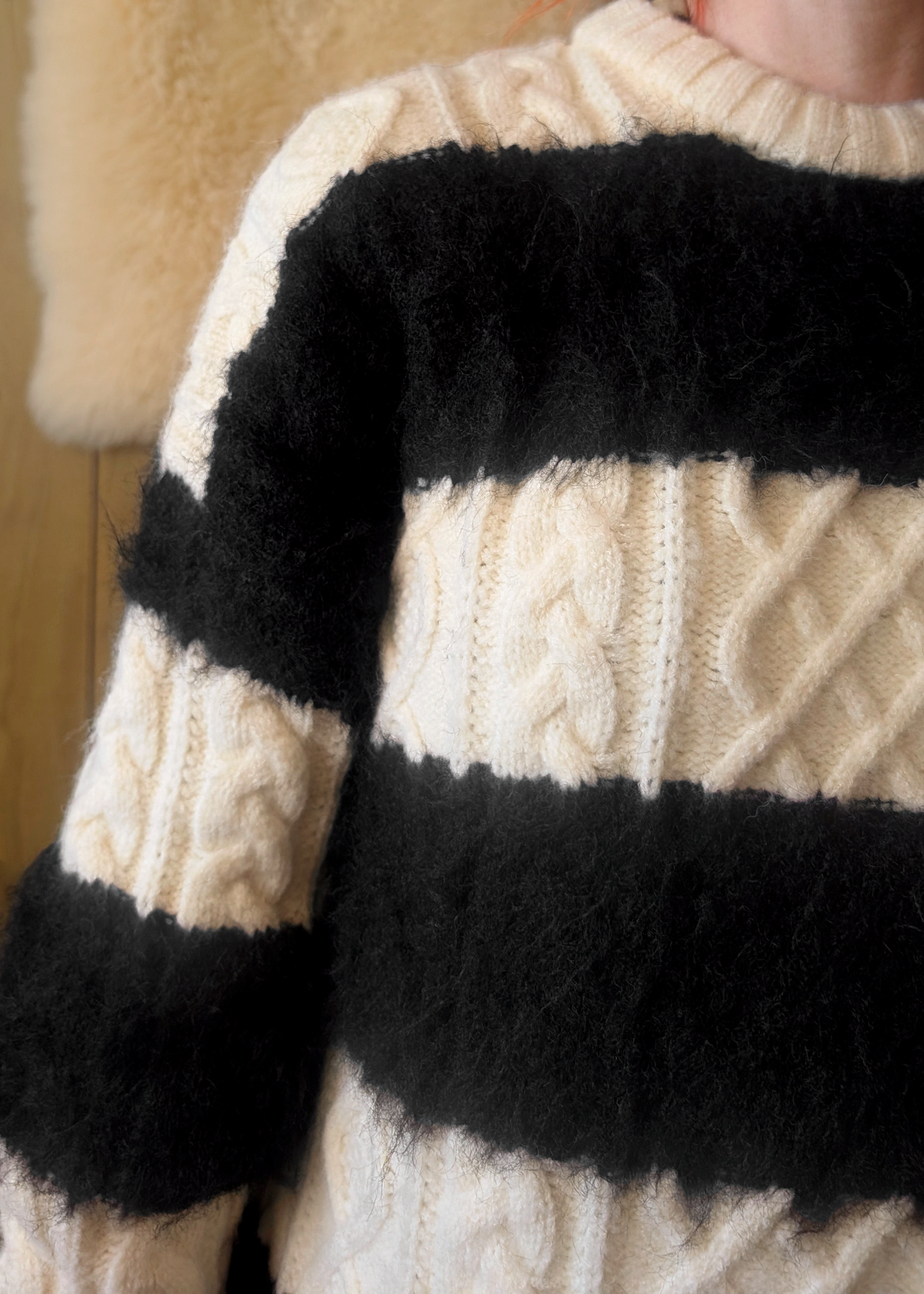 Close-up of a cream-colored sweater with black fuzzy horizontal striped panels
