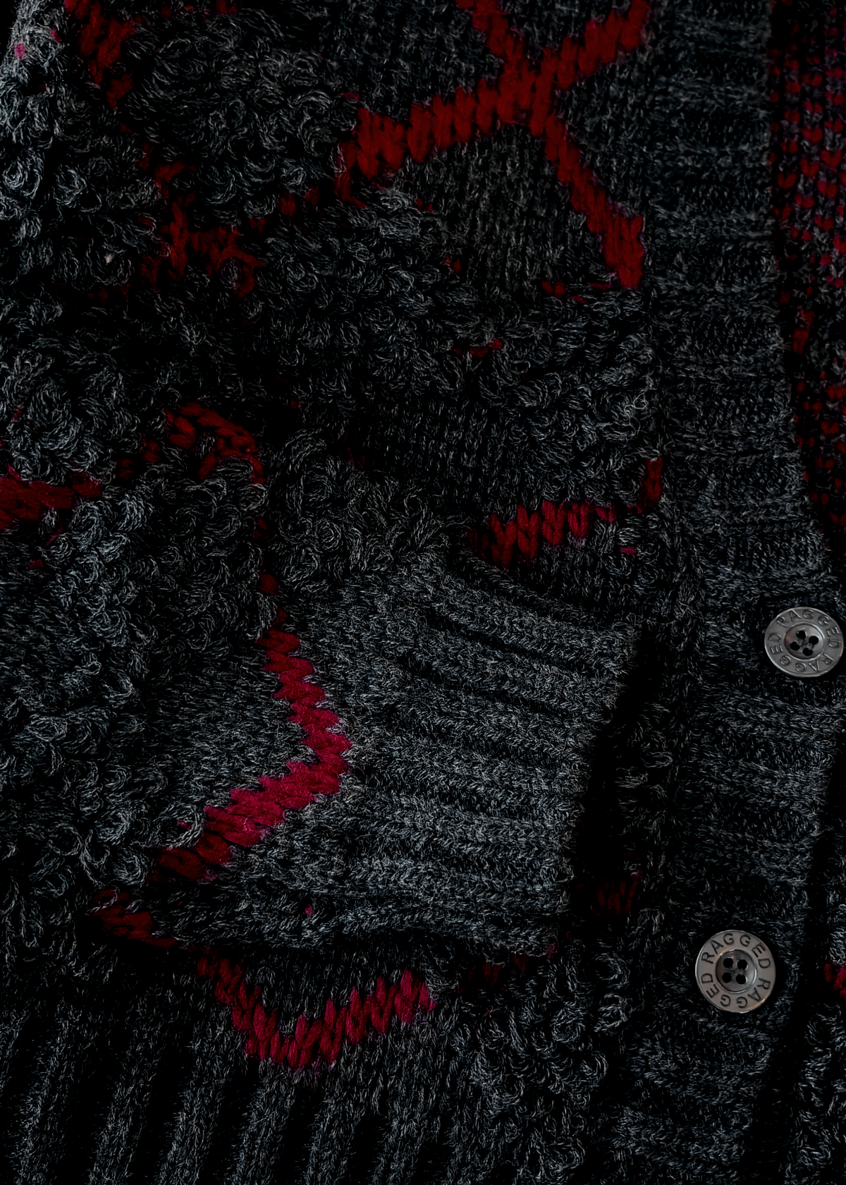Close-up of a dark gray textured fabric with red accents and buttons.