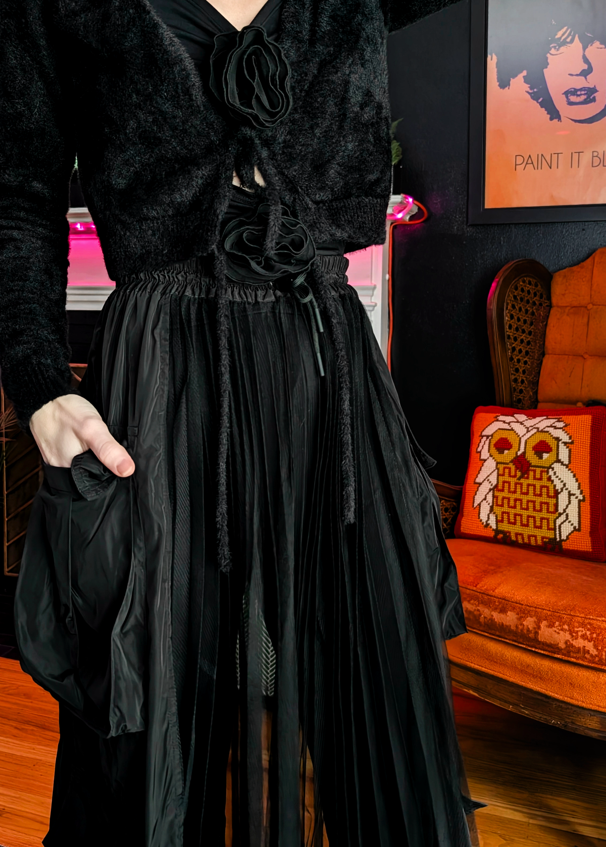 Person wearing a black sheer mesh cargo skirt with oversized pockets in an indoor setting.