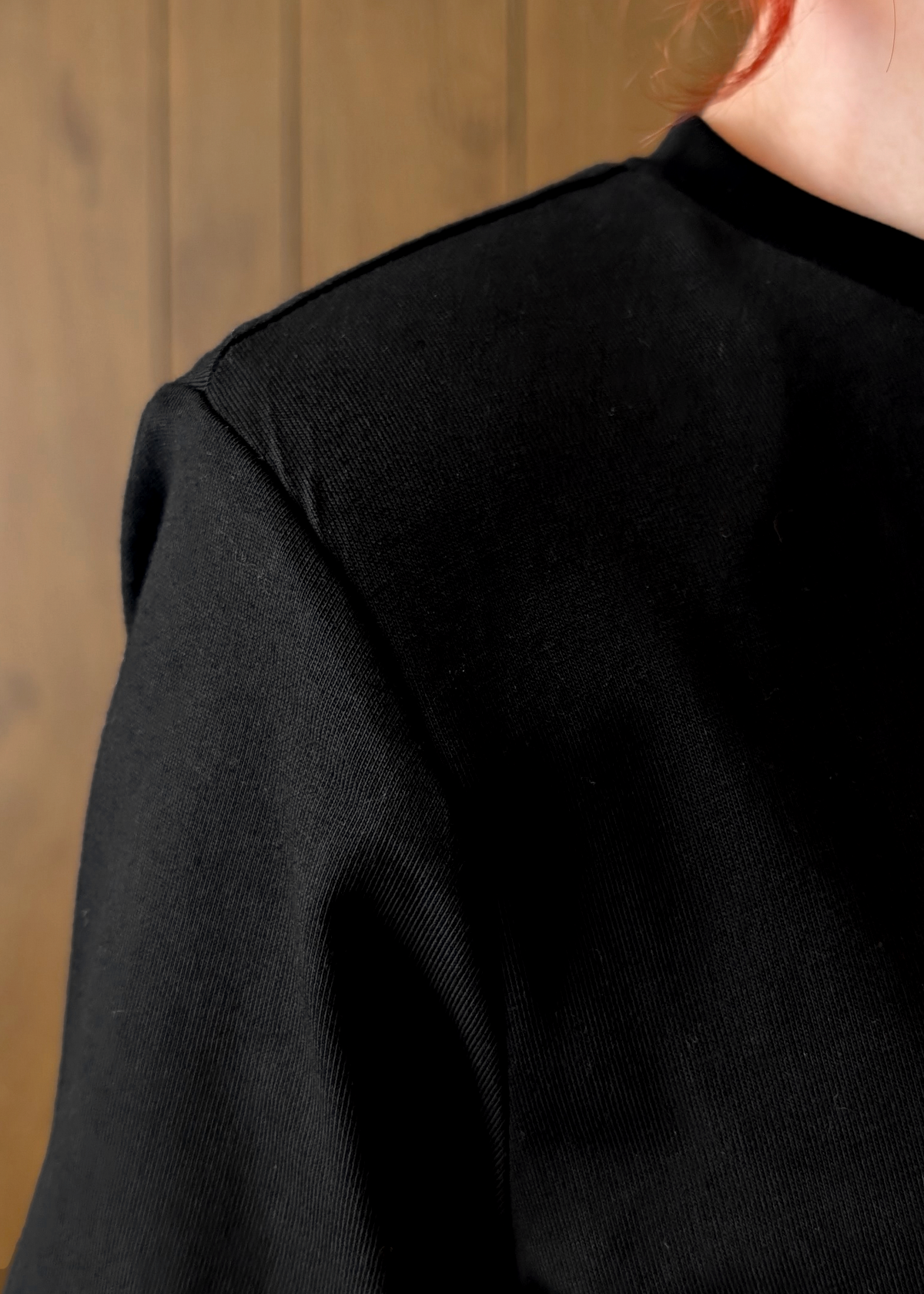 Close-up of a person wearing a black shirt against a wooden background