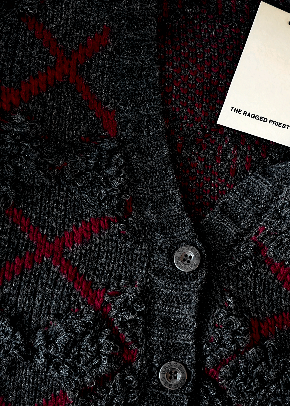 Dark gray cardigan with red pattern and 'The Ragged Priest' tag.