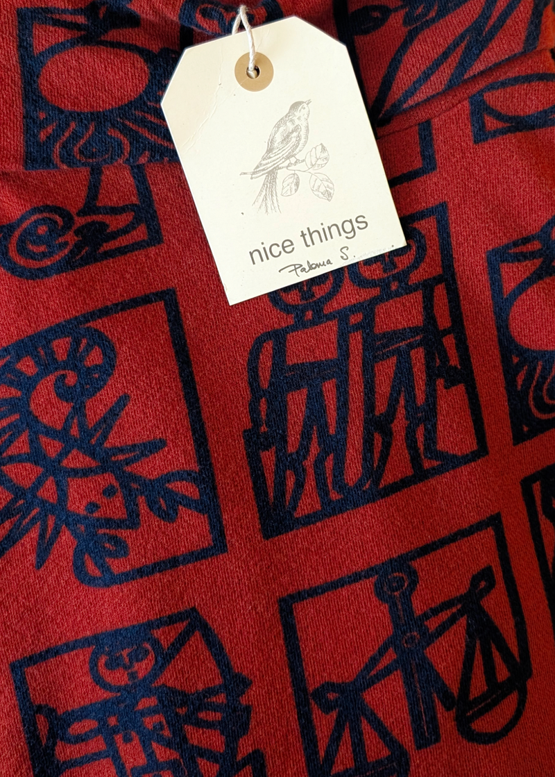 Red fabric with dark navy abstract zodiac patterns and a 'nice things' hang tag.