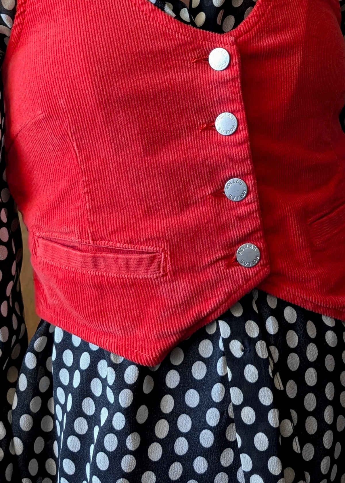 Red corduroy vest with silver buttons over a polka dot top