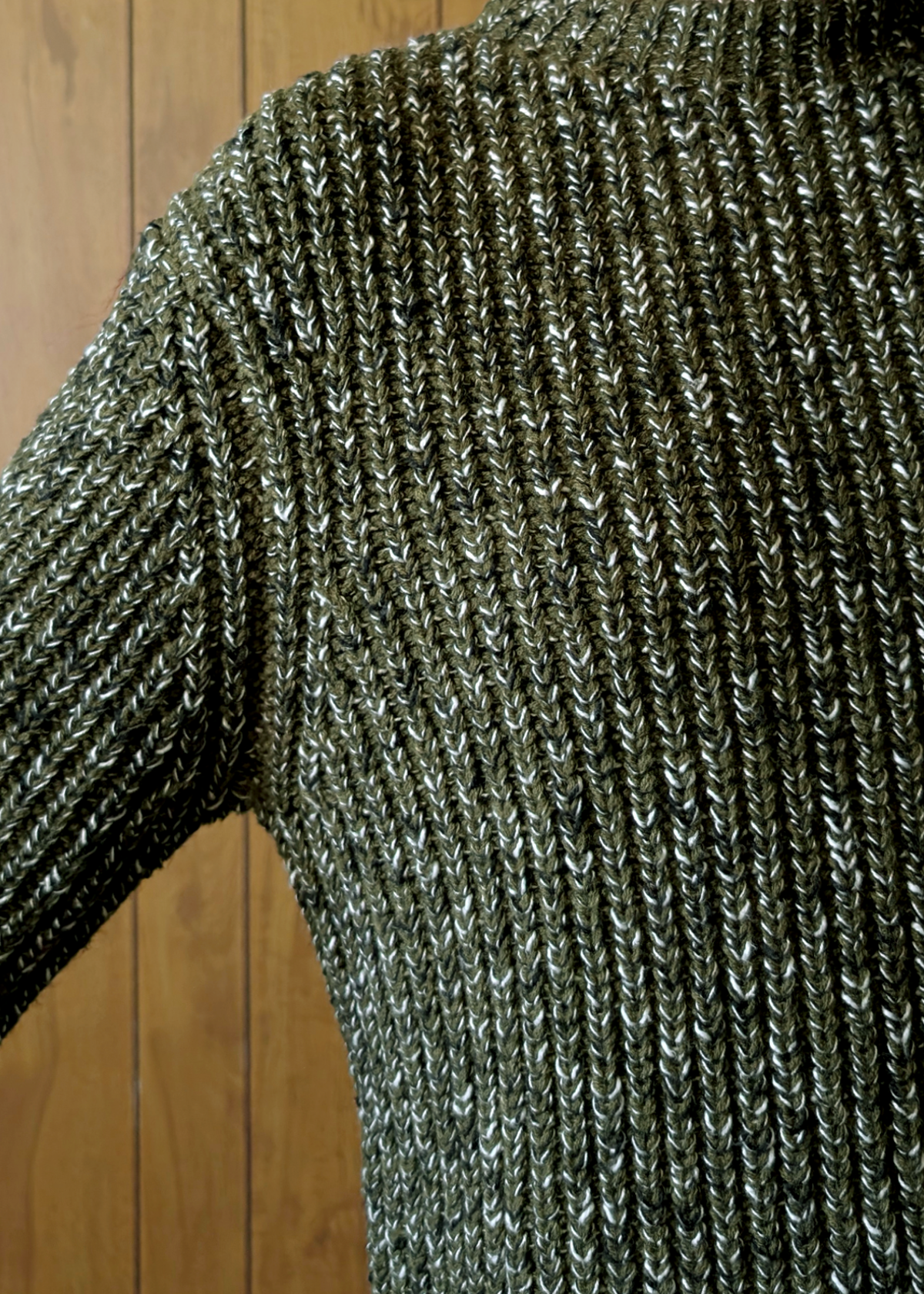 Close-up of a textured green sweater against a wooden background