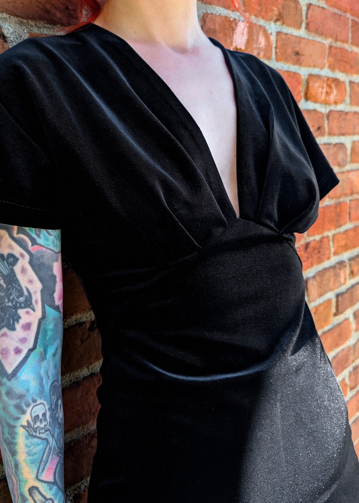 Details of the pleated bust and v-neckline on the black velvet dress 