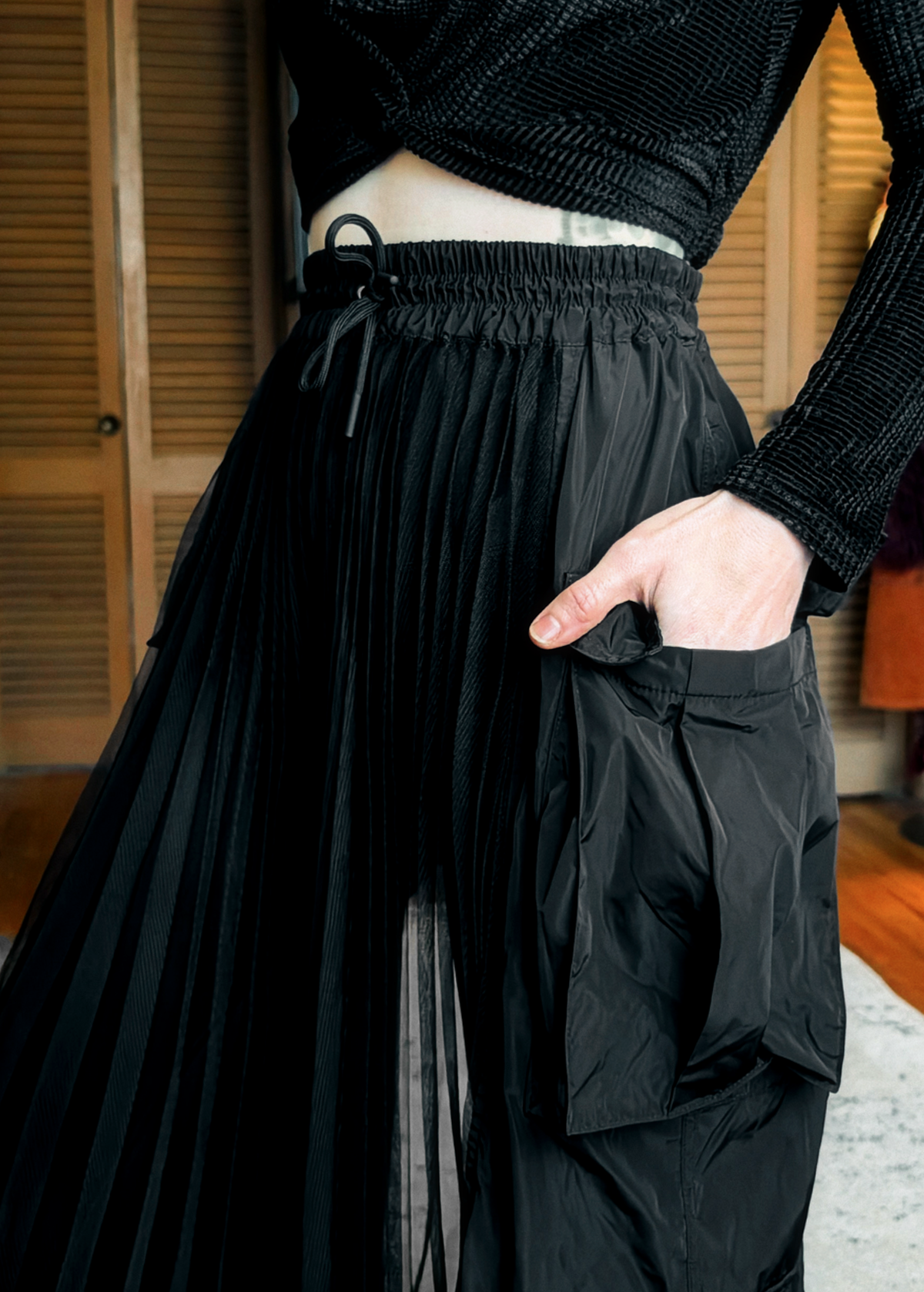 Person wearing a black sheer mesh cargo skirt  in an indoor setting.