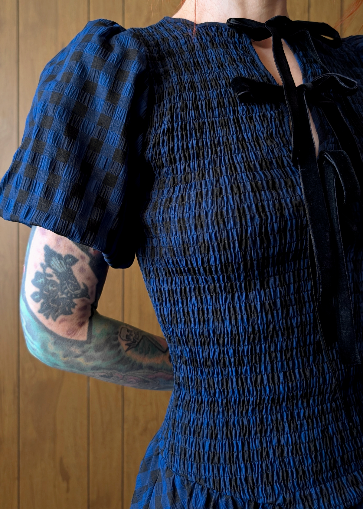 Person wearing a blue dress with puffed sleeves against a wooden background