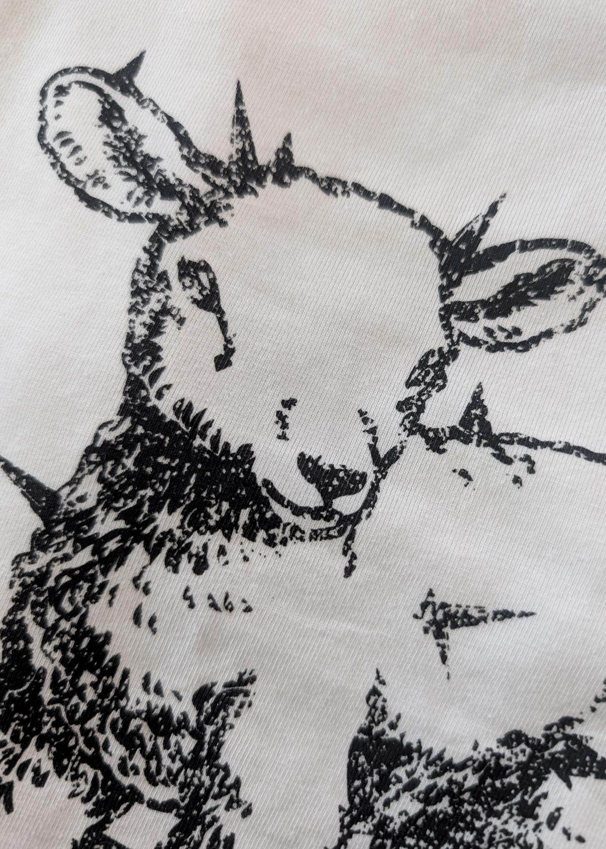 up close details of the spiked lamb graphic in black on an ivory t-shirt