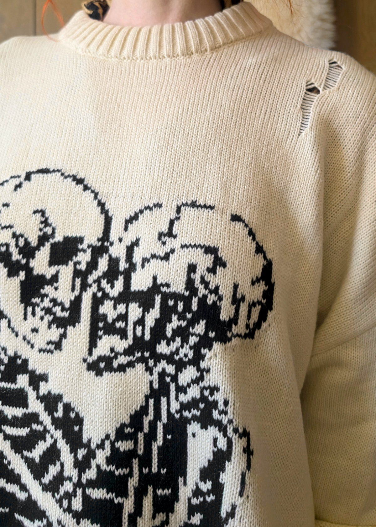 Close-up of a cream-colored sweater with black skeleton pattern