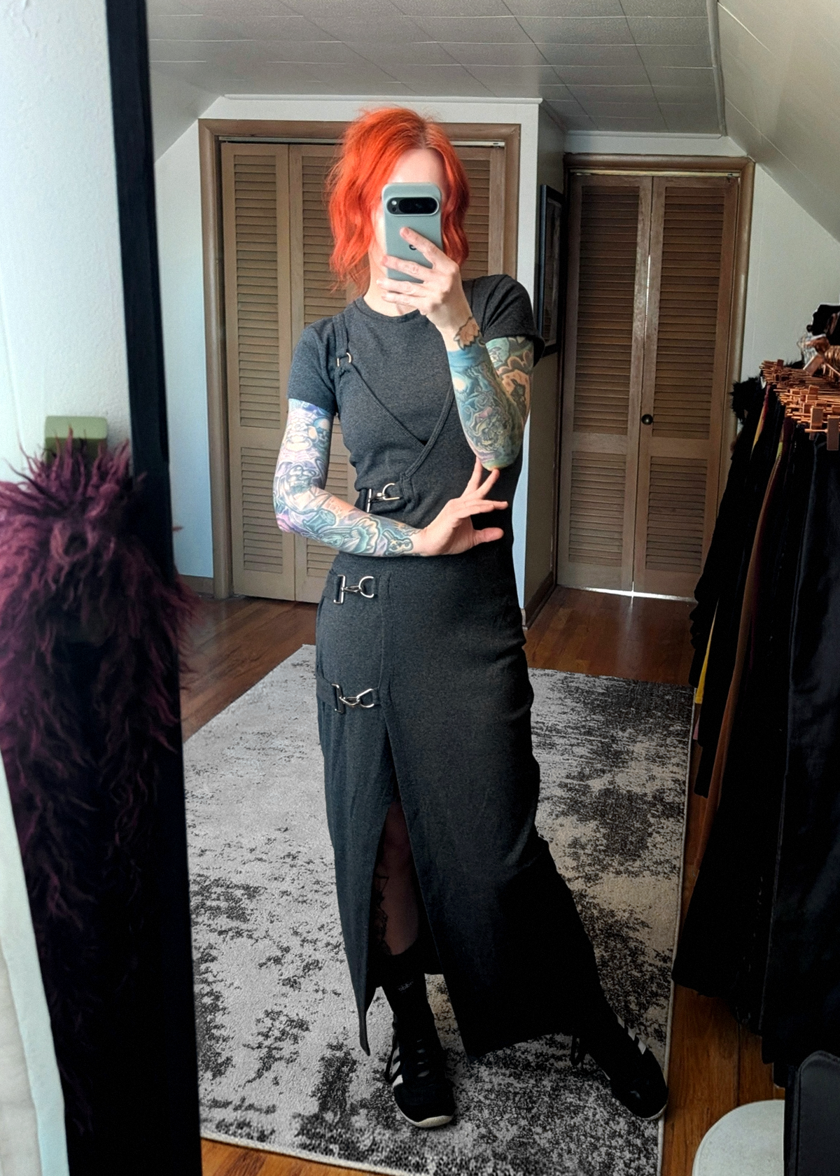 Person with red hair taking a mirror selfie wearing a charcoal grey ribbed tank midi dress styled under a charcoal grey ribbed tee