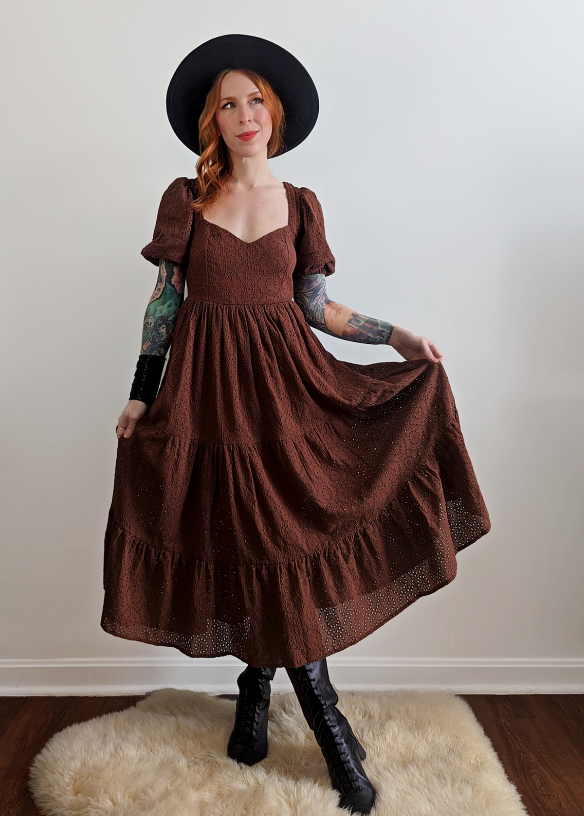 70s inspired prairie dress made of 100% eyelet cotton in a walnut brown colorway. Features puff sleeves, sweetheart neckline, smocked back with tie closure, and ruffled tiered skirt. 