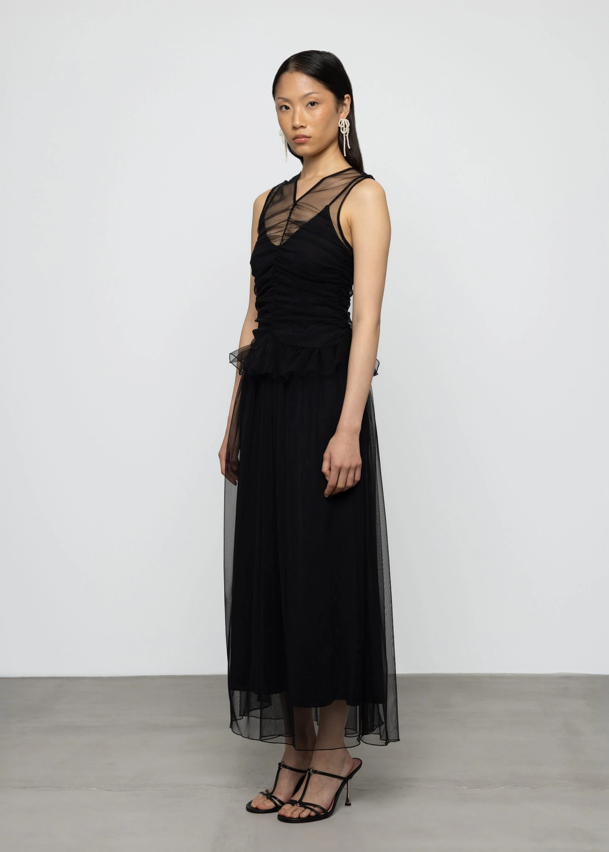Woman wearing a black dress with sheer panels on a white background